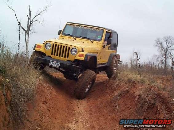 Yellow Jeep Wrangler climbing a dirt hill with a black top. Text on windshield reads 'DIAMOND OFF ROAD CUSTOMS'
