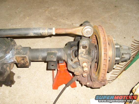 Front axle assembly on jack stands, showing tie rod, brake caliper, and rotor