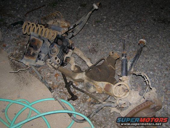 Disassembled front suspension parts including springs, shocks, and control arms on the ground