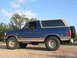 1996 Ford Bronco - This blue Ford Bronco is parked on a dirt road under a partly cloudy sky.