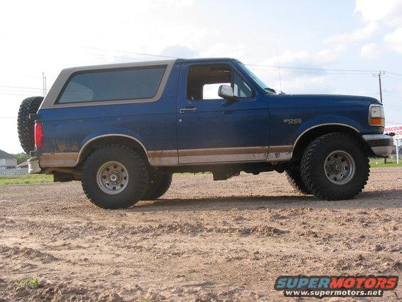 Blue 1996 Ford Bronco parked on dirt, side view with spare tire on rear door