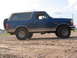 1996 Ford Bronco - Side view of a blue 1996 Ford Bronco with a spare tire mounted on the back.