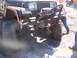 1989 Ford Bronco - A heavily modified Jeep Wrangler is shown in a muddy, off-road setting with people and another vehicle nearby.