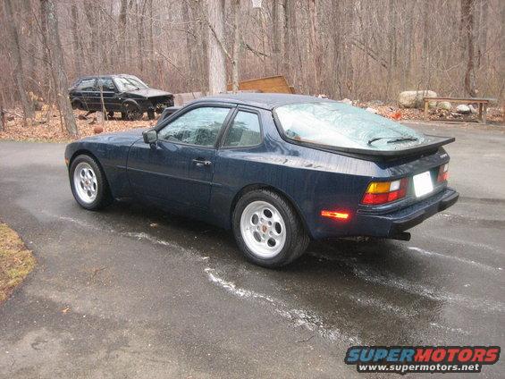 dark blue coupe parked on driveway, another black car in background