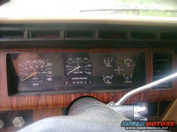 Dashboard gauges and wood trim inside a vehicle. Speedometer shows 35 mph, tachometer shows 1500 RPM