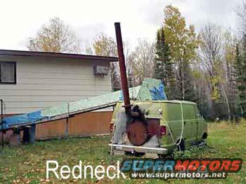 Green van with a tall pipe attached to the rear, parked in a grassy area