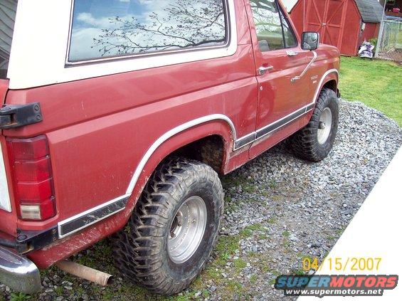 Red Ford Bronco, side view, showing off-road tires and white roof