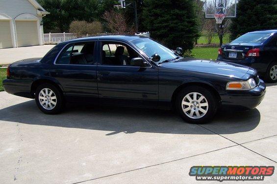 Dark 2003 Ford Crown Victoria parked on concrete driveway, another car behind it