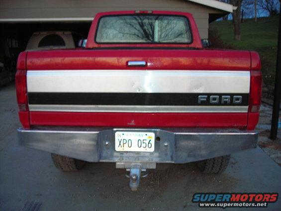 Rear view of a red Ford pickup truck with a chrome bumper and a license plate that reads XPO 056