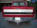 1995 Ford F-250 - The rear of a red Ford pickup truck is shown, a chrome bumper and a multi-colored tailgate stripe.