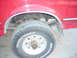 1995 Ford F-250 - Close-up of the rear wheel assembly of a red truck, revealing suspension components and tire details.