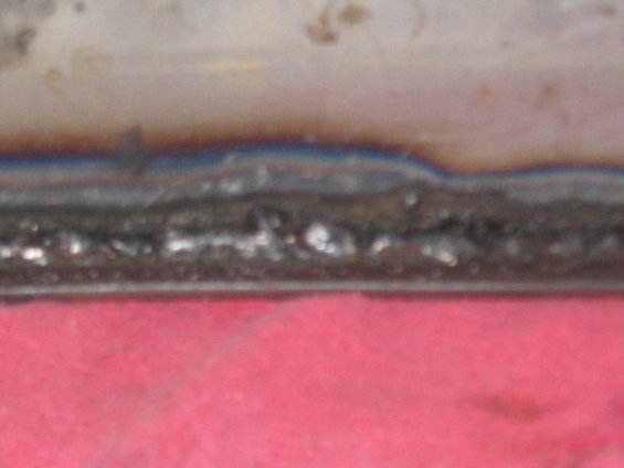 Close-up of a welded metal seam over a pink surface