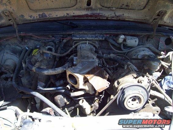 Engine bay with exposed engine components and wiring. The engine appears dirty and possibly modified
