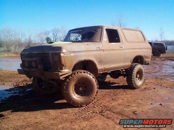 Muddy 1978 Ford Bronco on dirt track with another vehicle in background