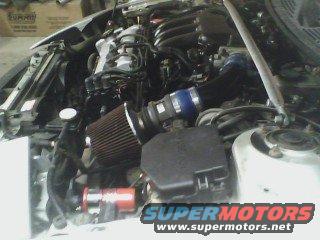 Engine bay with a cone air filter and some aftermarket parts. SuperMotors logo visible