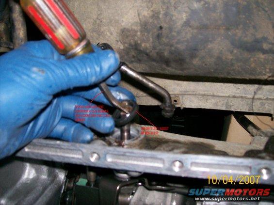 Blue gloved hand using a screwdriver and pliers on a metal part, with red text annotations. Date 10/04/2007 visible