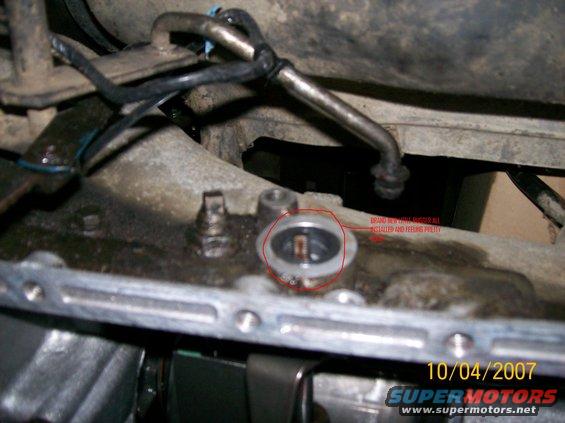 Close-up of a vehicle's transmission with a red circle around a part labeled 'BRAND NEW THROTTLE BUSHING INSTALLED AND FEELING PRETTY'