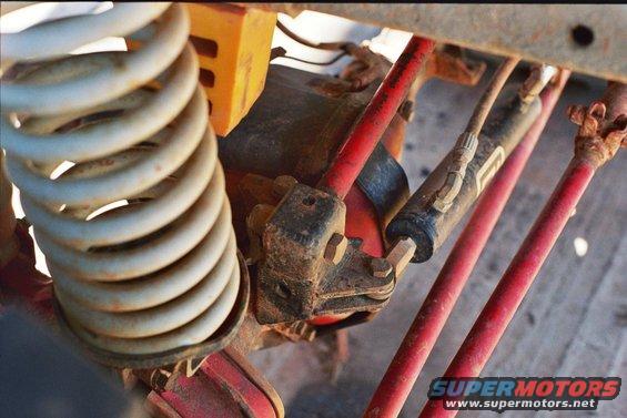 Close-up of suspension coil, shock absorber, and red painted metal rods