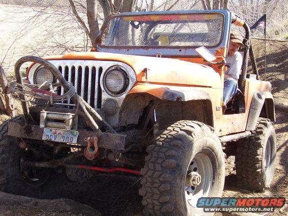 Orange Jeep CJ with a winch and off-road tires, front view