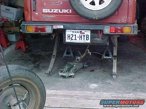 Red Suzuki Samurai rear bumper with Texas license plate H21-HYB, supported by jack stands