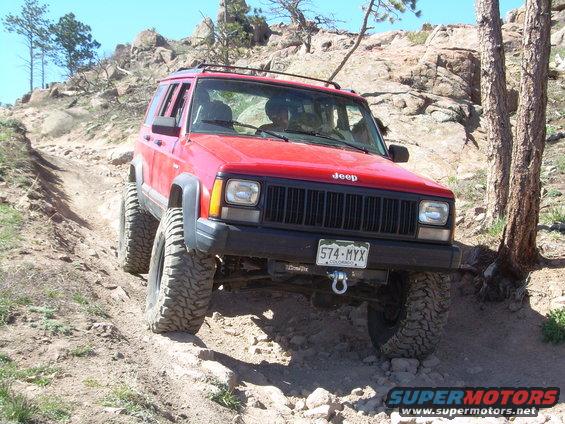Red 1996 Jeep Cherokee on a rocky, off-road trail with large tires
