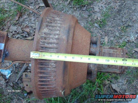 Rusty rear axle assembly with a tape measure across it, showing approximately 8 inches
