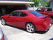 2006 Dodge Charger - A red 2006 Dodge Charger sedan is parked in a driveway, with a red pickup truck visible behind it.