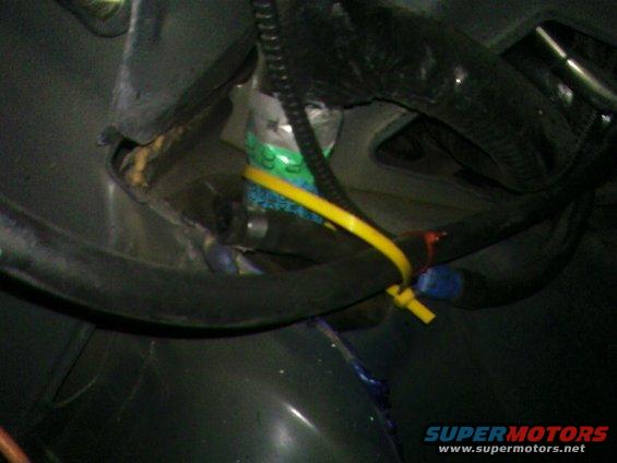 Close-up of a vehicle's wiring harness with yellow and blue zip ties, and a green-labeled component