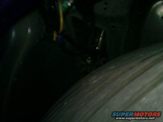Close-up of a car's wheel well with visible wiring and part of the tire