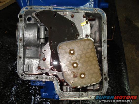 Open transmission pan with filter removed, showing internal components and some fluid