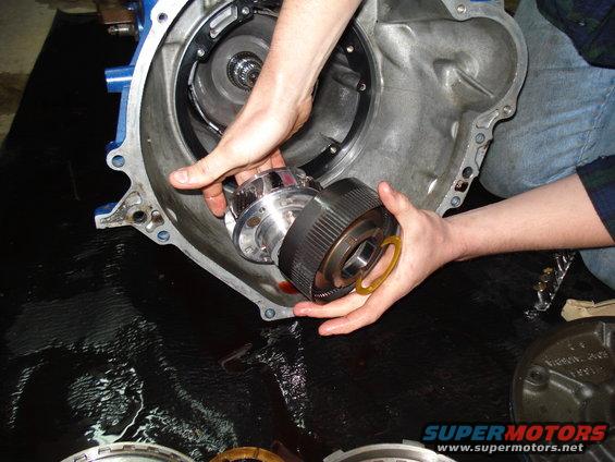 Hands removing a torque converter from a transmission housing