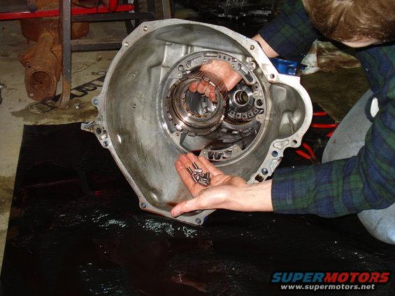 Person holding small metal parts over an open transmission case