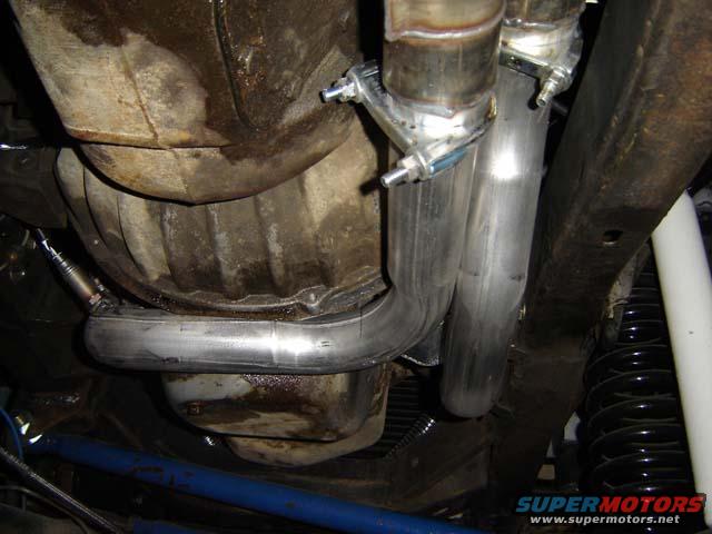 Underneath view of a vehicle's exhaust pipes, fuel tank, and suspension components
