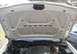 2000 Ford Crown Victoria - The underside of a white car's hood is open, revealing the engine compartment and a portion of another vehicle in the background.