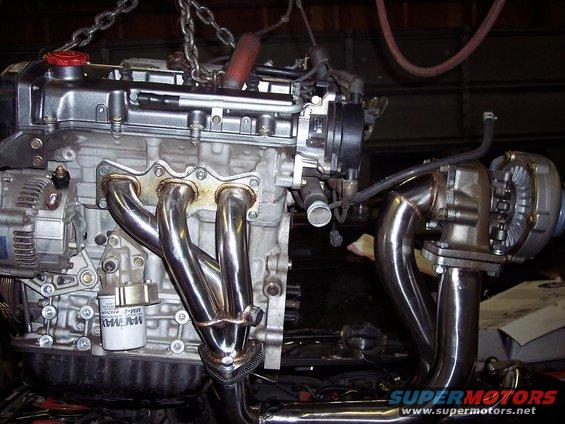 Engine with turbocharger and shiny exhaust manifold, suspended by chains