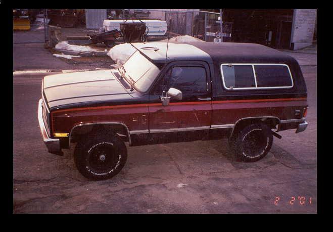 Maroon and black SUV with a camper shell, seen from the front-right