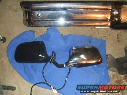 chrome bumper and two side mirrors, one black, one chrome, on blue cloth
