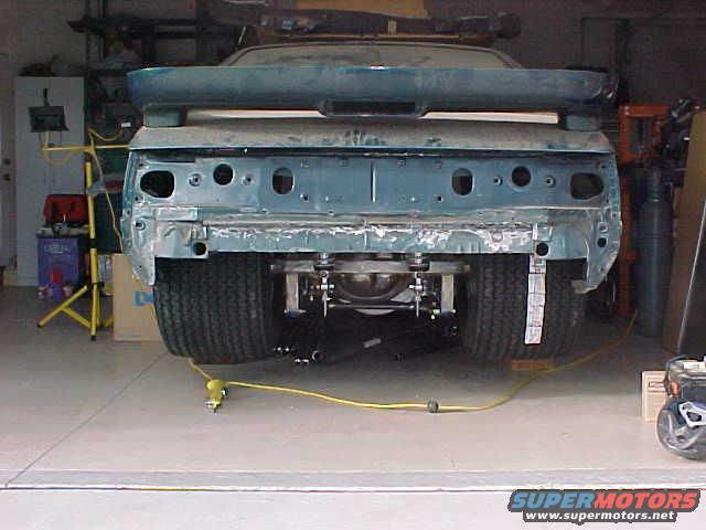 Rear view of a 1992 Ford Mustang with spoiler, undergoing restoration