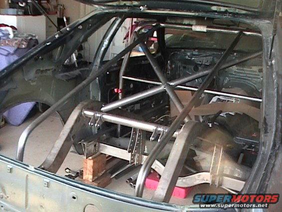 car interior stripped down with a roll cage installed, rear axle visible