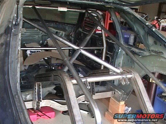 Interior of a car with a roll cage, stripped interior, and unfinished bodywork