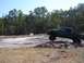 1989 Ford Bronco - A modified pickup truck navigates a challenging off-road course, with one wheel in the air.