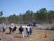 1989 Ford Bronco - A Jeep Wrangler performs a jump at an off-road event, with spectators observing the action.
