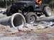 1989 Ford Bronco - A modified off-road vehicle tackles a challenging course with large concrete pipes as obstacles.