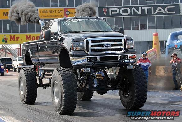 Black lifted Ford F-Series truck with large tires emitting black smoke, viewed from a 3/4 front angle
