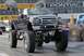 1996 Ford Bronco - A heavily modified black Ford truck with massive tires spews dark smoke during an event.