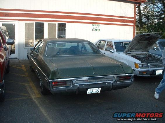 Green sedan parked next to a white car with its hood up. License plate reads 209-JZT