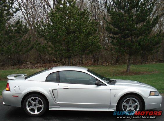Silver coupe with spoiler parked outdoors, side view
