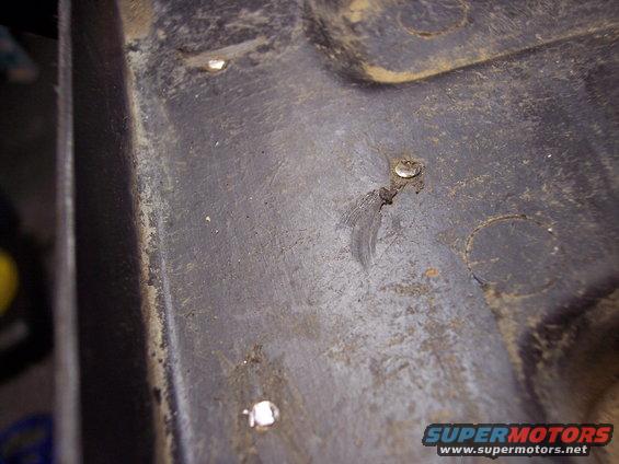 Close-up of a dark, textured interior car panel with visible rivets and some dirt