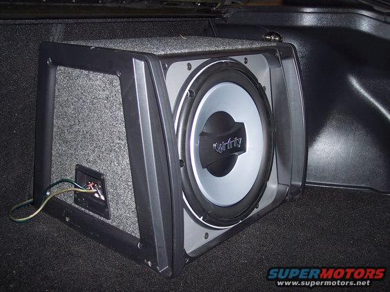 Car subwoofer in trunk, grey carpeted box with black trim, silver speaker cone, Infinity logo