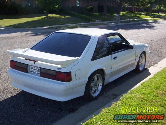 White 1991 Ford Mustang hatchback parked on a residential street, rear 3/4 view